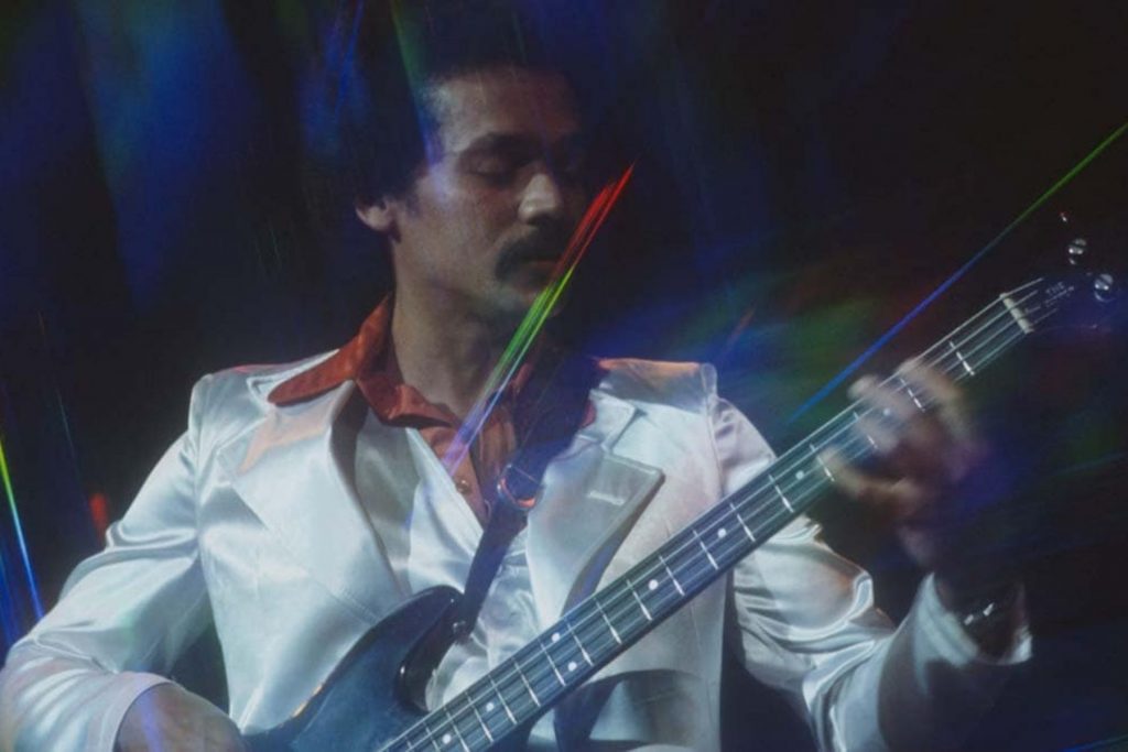 Una imagen de archivo de un joven Bobby Valentín tocando el bajo en el escenario durante los años de auge de la salsa, mostrando los inicios de su carrera.