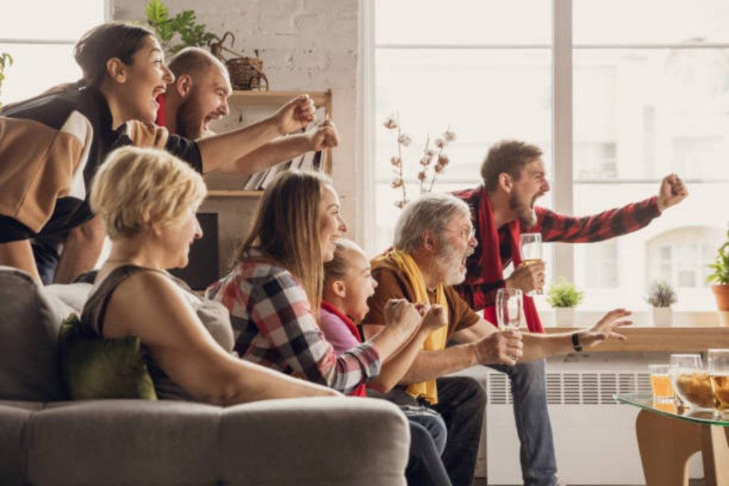 Familia de varias generaciones celebrando un gol en el sillón de su casa, un ejemplo de cómo las cábalas del Mundial unen a abuelos, padres e hijos.