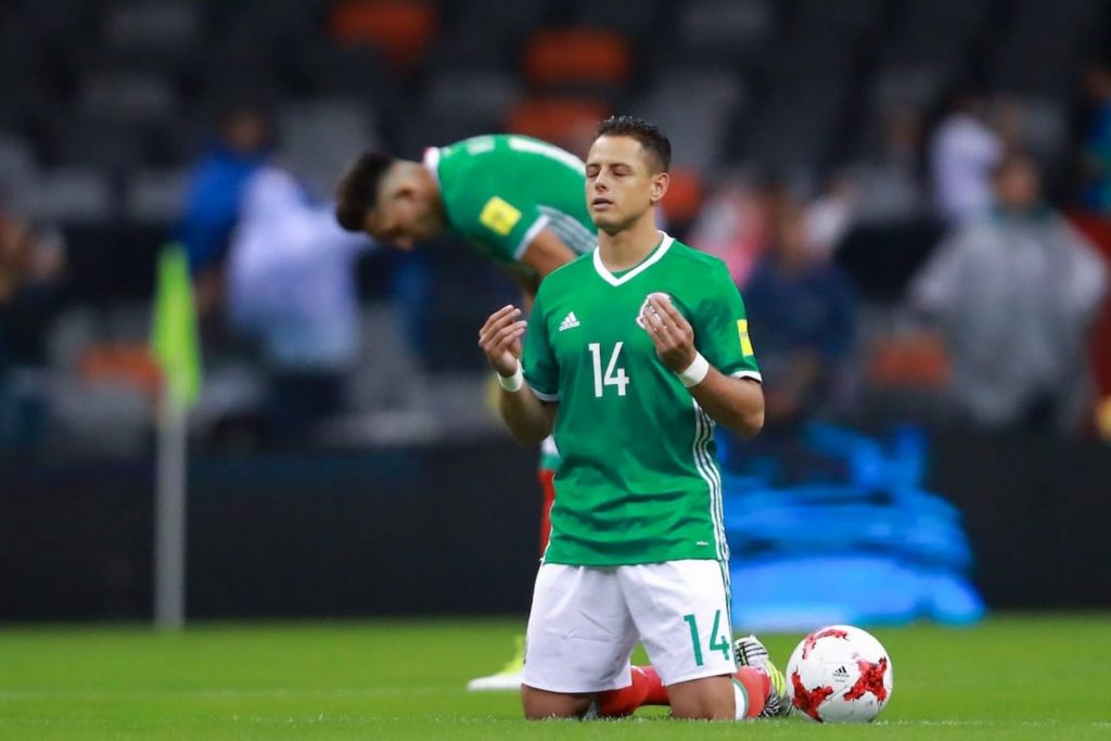 El futbolista Javier 'Chicharito' Hernández rezando en la cancha, un ejemplo de los rituales de fe que jugadores