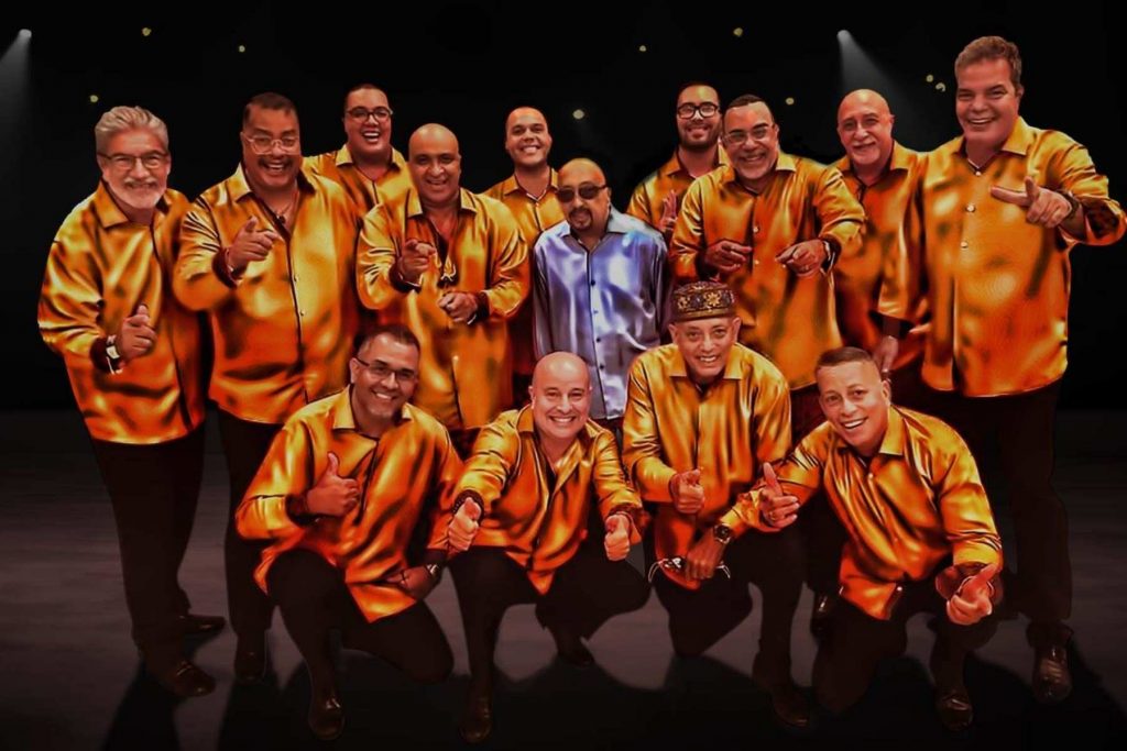 El fundador de La Sonora Ponceña, Don Quique Lucca, rodeado por los músicos de la orquesta. Una imagen que representa el legado y la herencia familiar de una de las instituciones de la salsa.