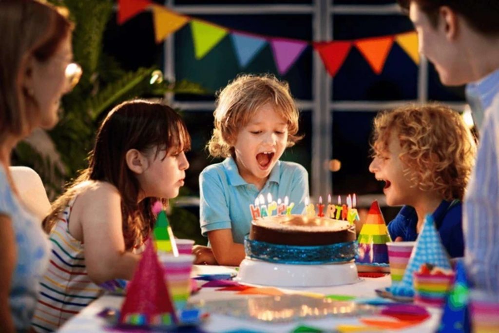 Unos niños emocionados alrededor de un pastel de cumpleaños, representando la analogía de los delanteros, que son como los sobrinos que solo piensan en el pastel (el gol).