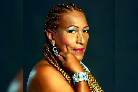 Imagen promocional de Yolanda Rivera, la Dama de la Salsa, sonriendo y haciendo una señal de paz con los dedos.